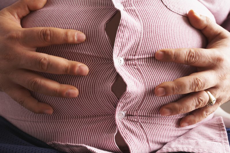Man Holding His Large Belly --- Image by © Peter Reali/Corbis