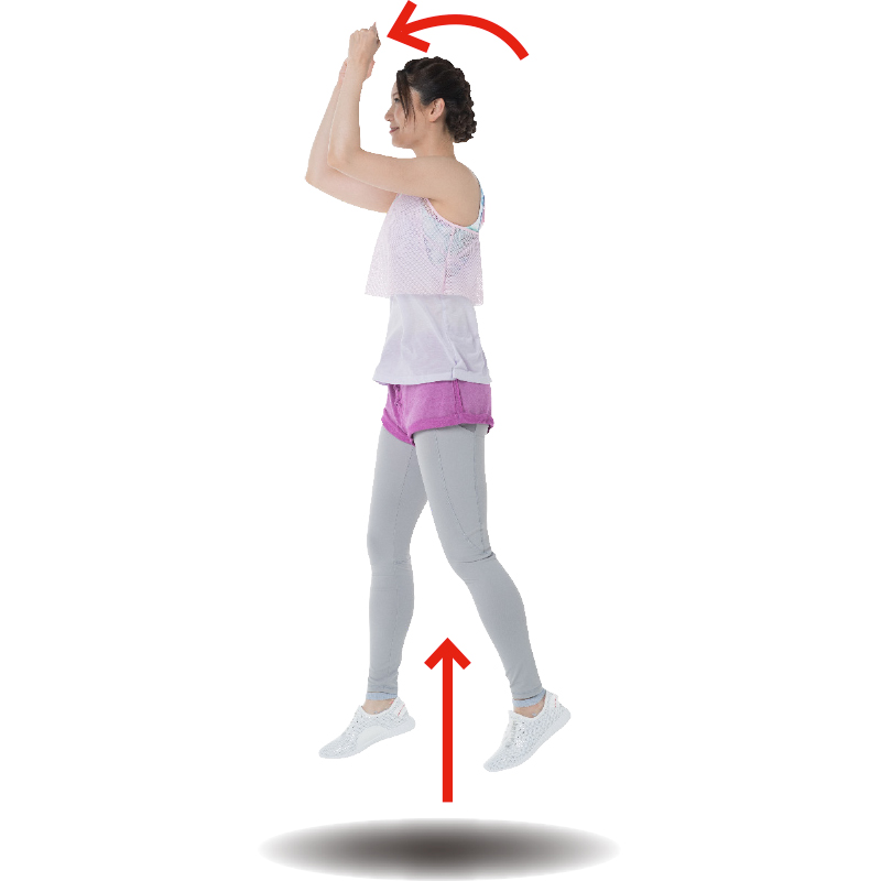 両ひじを曲げて肩の高さに上げ、足を前後の開いたままジャンプするトレーニング着の女性