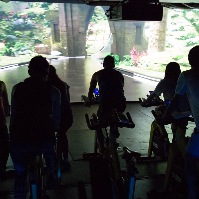 「CYCLE & STUDIO R」VRサイクル『THE TRIP』の画面と体験者の後ろ姿