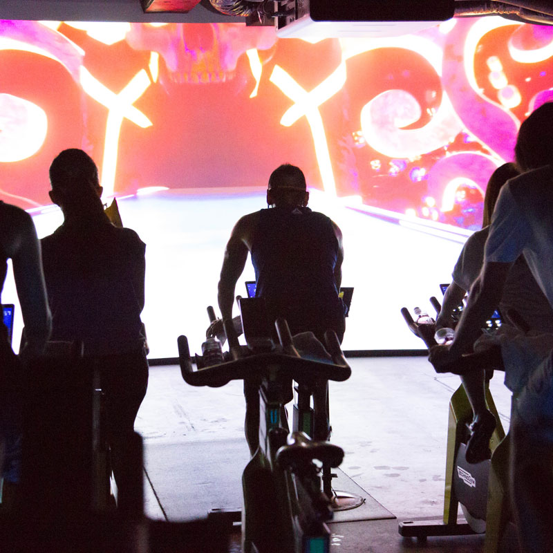 「CYCLE & STUDIO R」VRサイクル『THE TRIP』の画面と体験者の後ろ姿