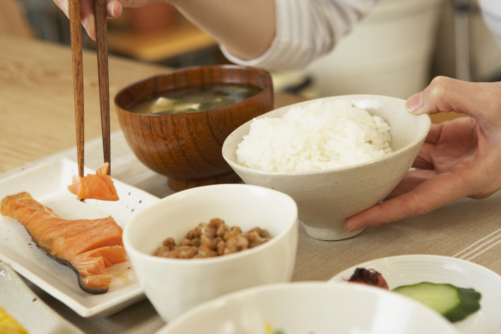 和朝食がテーブルに並んでいる。ご飯、味噌汁、納豆、焼鮭など