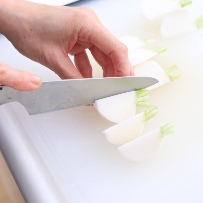 「春野菜のコブサラダ」材料のかぶを包丁で切っている