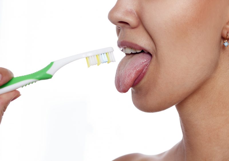 歯ブラシで舌を磨いている女性