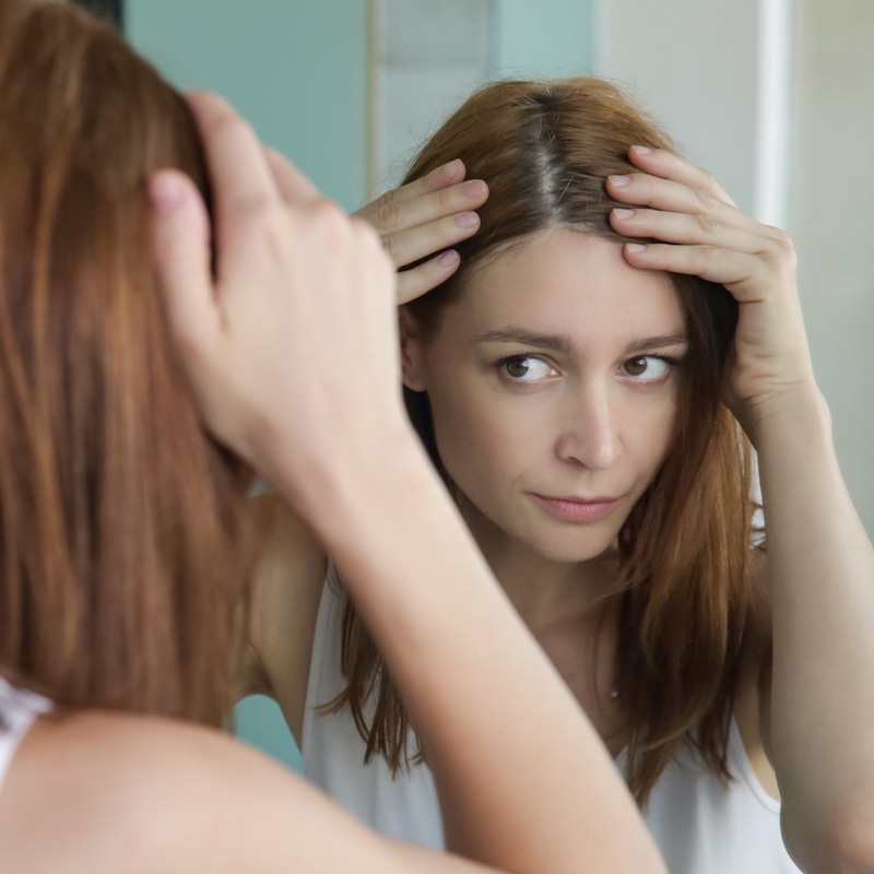 鏡で頭皮をチェックする女性