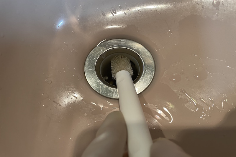 KEYUCAのすき間掃除シリーズ みぞ洗いブラシで洗面所のシンクの排水口の掃除をしている様子