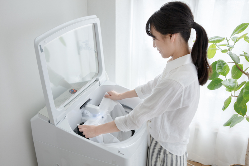 アクア　全自動洗濯機『Prette AQW-GVX140J』の自動部分洗いをするためにワイシャツの襟部分を当てている女性