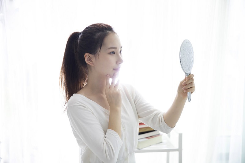 手鏡で自分の顔を見ている女性