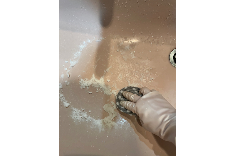 ケユカのsocio 泡立ちクロススポンジ 2枚セットに重曹をつけて、ゴム手袋をして洗面台のシンクを掃除している