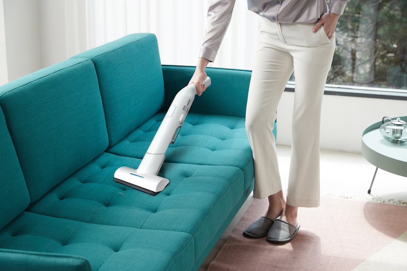 レイコップ・ジャパン『レイコップGO』を女性が右手で持ちソファを掃除している