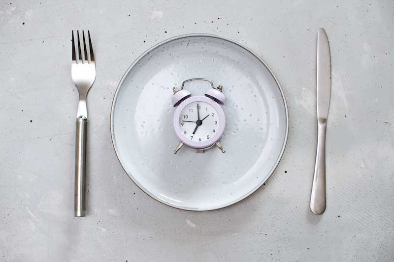 白い皿の上に7時をさす時計が置かれ、サイドにはナイフとフォークが置かれている