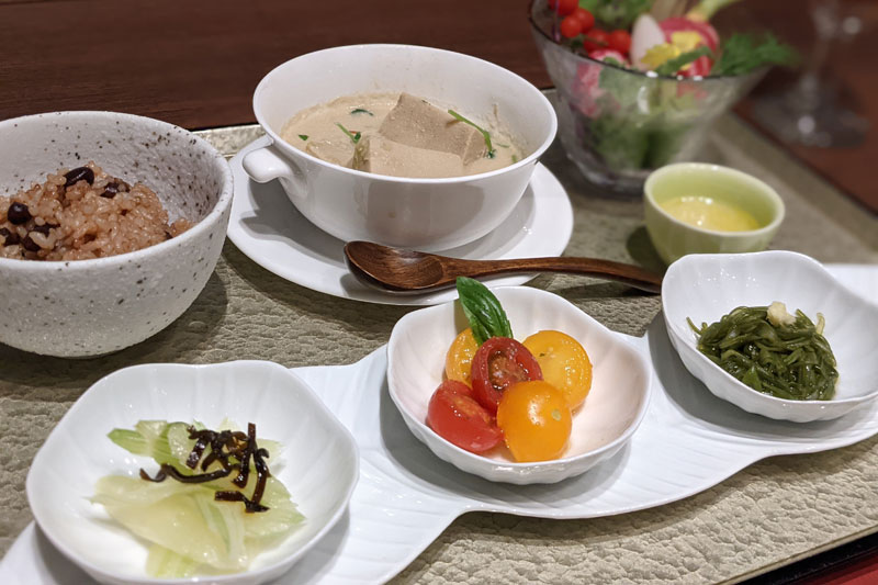 発芽玄米に、高野豆腐と豆乳の坦々スープ、彩野菜など。効能が書かれたメニューが添えられている