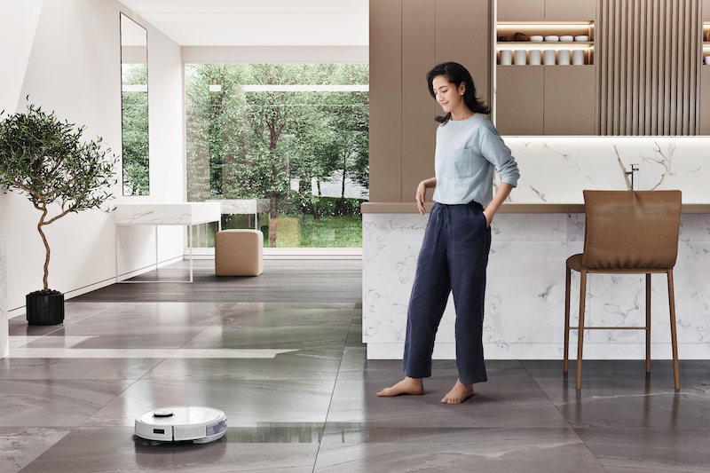 ロボット掃除機エコバックス『DEEBOT T9+』が床を掃除していて近くに女性がいるリビング