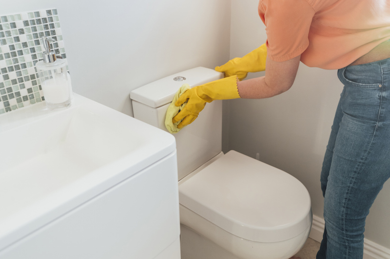 黄色の手袋をしてトイレ掃除をしている女性