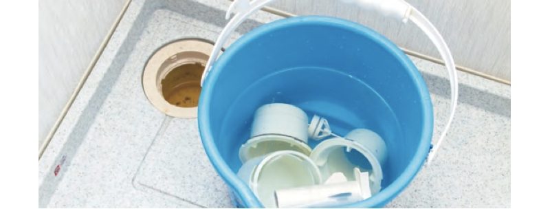 塩素系洗剤を混ぜた洗浄液を入れたバケツに排水口の部品が浸け込まれている