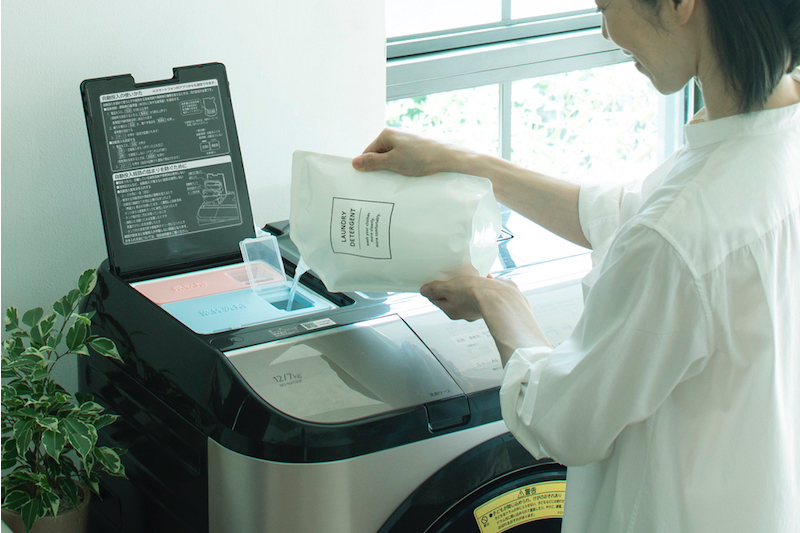 日立グローバルライフソリューションズ『ドラム式洗濯乾燥機　BD-NX120GL』の旧型に洗剤を注ぎ込んでいる女性