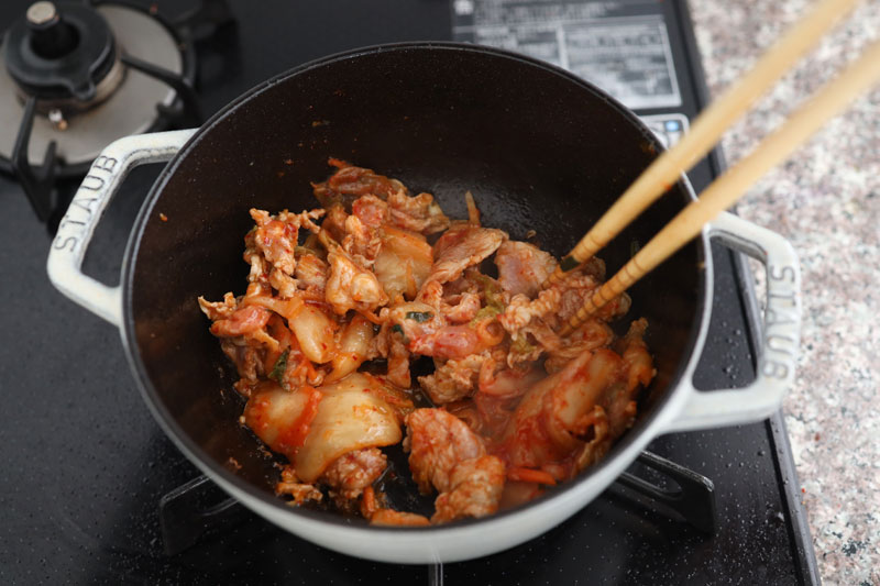 鍋にごま油、おろしにんにくを入れ、弱火で熱する。香りがたってきたらキムチと豚こま肉を加え、中火で炒める