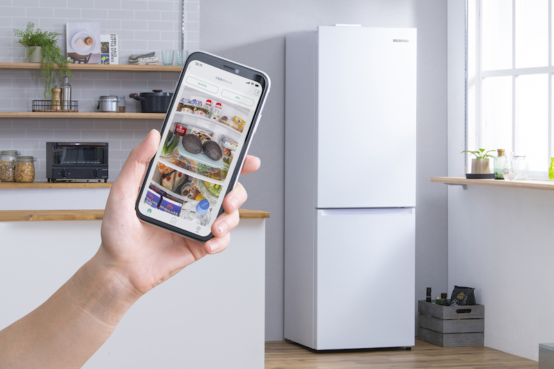 アイリスオーヤマ『STOCK EYE カメラ付き冷凍冷蔵庫 296L』 ※中容量・右開きタイプ のあるキッチンで、冷蔵庫に向かってスマホ後かざしている手元