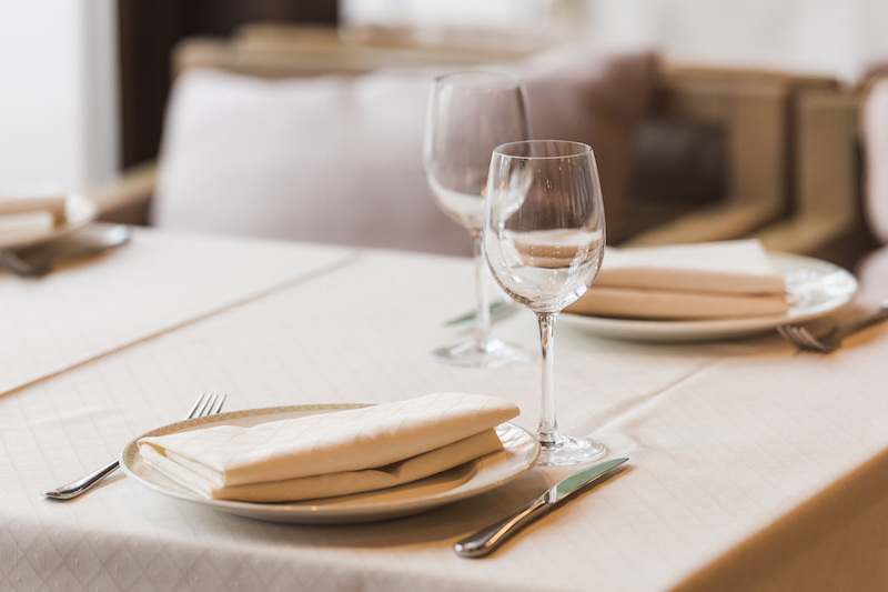 グラスと皿とナプキンなどが並ぶレストランのテーブル