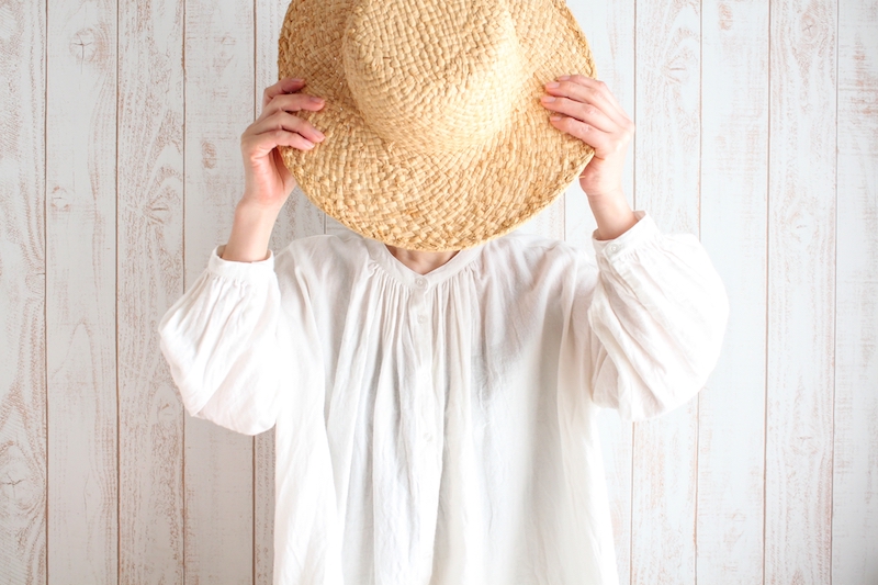 麦わら帽子で顔を隠す女性