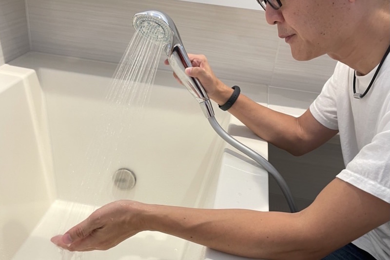 お風呂のソムリエ・松永武さんがリファのシャワーヘッドで水を出して片手で受けている