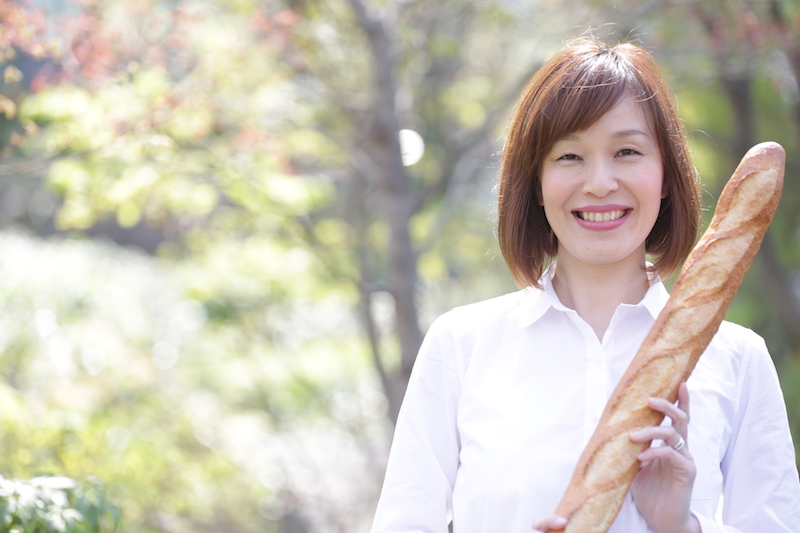 パンマニア・片山智香子さんがフランスパンを手に笑っている
