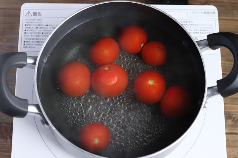 ミニトマトのヘタを取り、ヘタの反対側に爪楊枝を刺す。鍋いっぱいに水をいれ沸かしてミニトマトを入れ、30秒ほどして皮が弾けたら氷水に取り出す