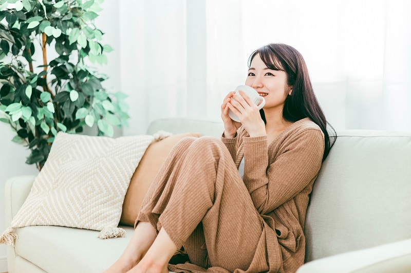 ソファでお茶を飲んでリラックスしている女性