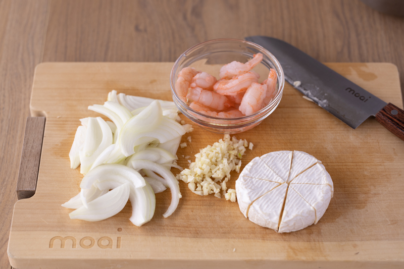 玉ねぎは薄切り、にんにくはみじん切りに。カマンベールチーズは一口大に切る。冷凍えびは流水で解凍し水を切る