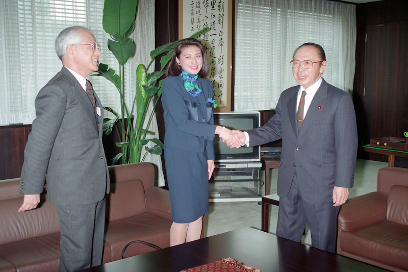 渡辺美智雄外相（当時）と握手をかわされる雅子さま。隣には父親の小和田恆さん（左）も（1993年2月9日、Ph／JIJI PRESS）