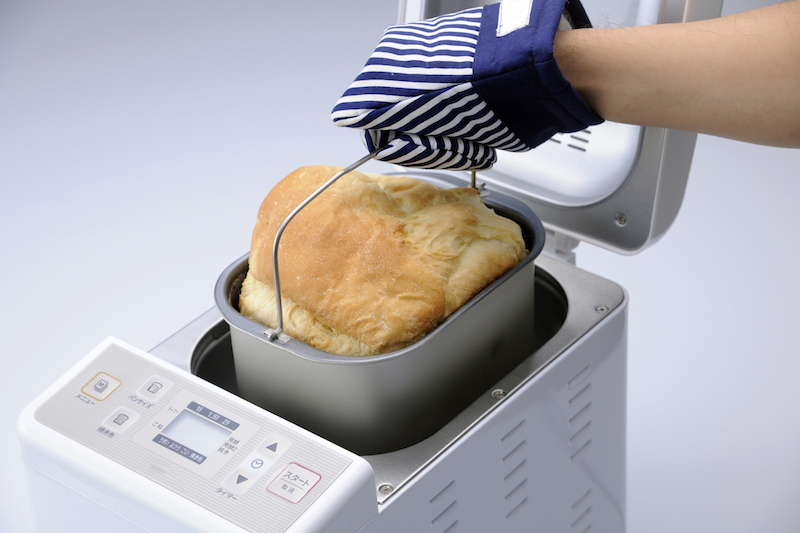 パン焼き機から焼けたパンを取り出す手元
