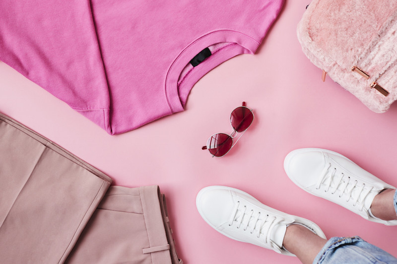 ピンクのTシャツとピンクのバッグと、ピンクのパンツと白いスニーカーを履いた足元