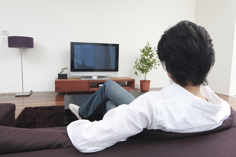 男性がソファに座ってテレビを見ているイメージ