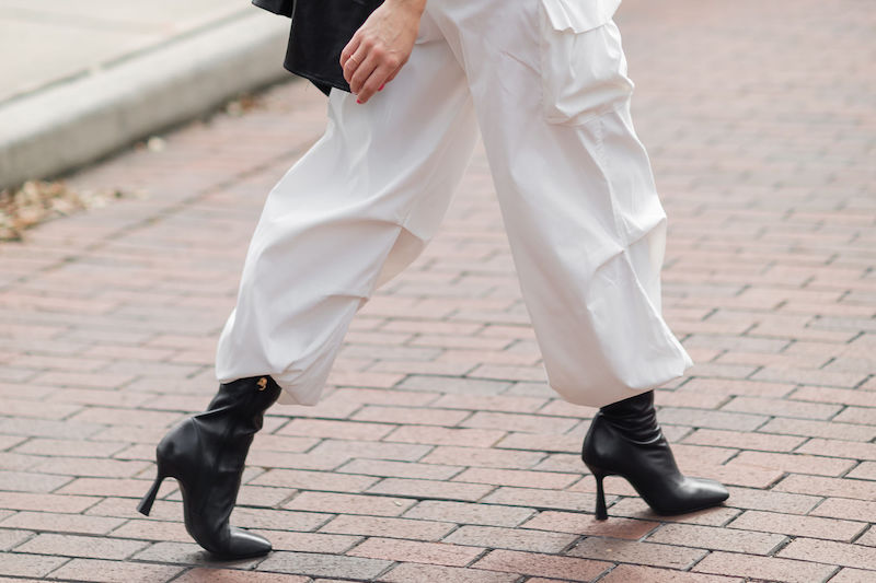 黒のブーツに白のカーゴパンツに黒の革ジャケットを羽織った女性の足元