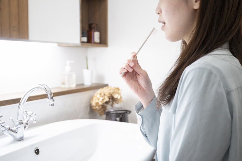 洗面化粧台で歯磨きをする若い女性