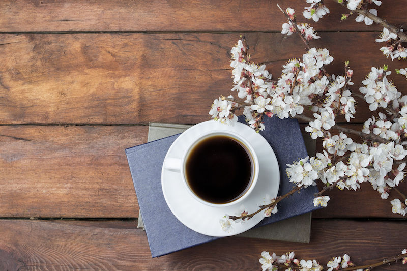 桜の枝とコーヒーが入ったカップと本