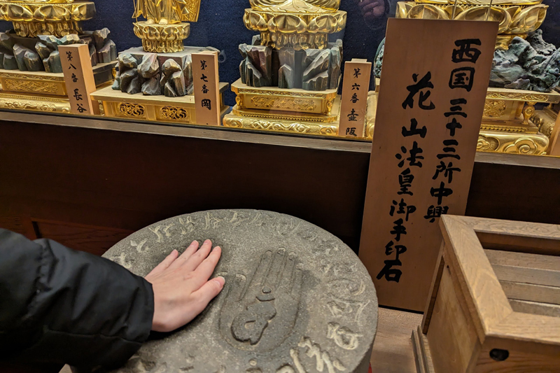 岡寺には、NHK大河ドラマでも描かれた花山法王御手印石があり手をあわせ祈ることができる。出家後の花山法王は功績が高く評価されているという（表現確認）